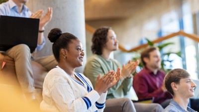 Image of a group of people sitting and applauding in a modern conference hall.